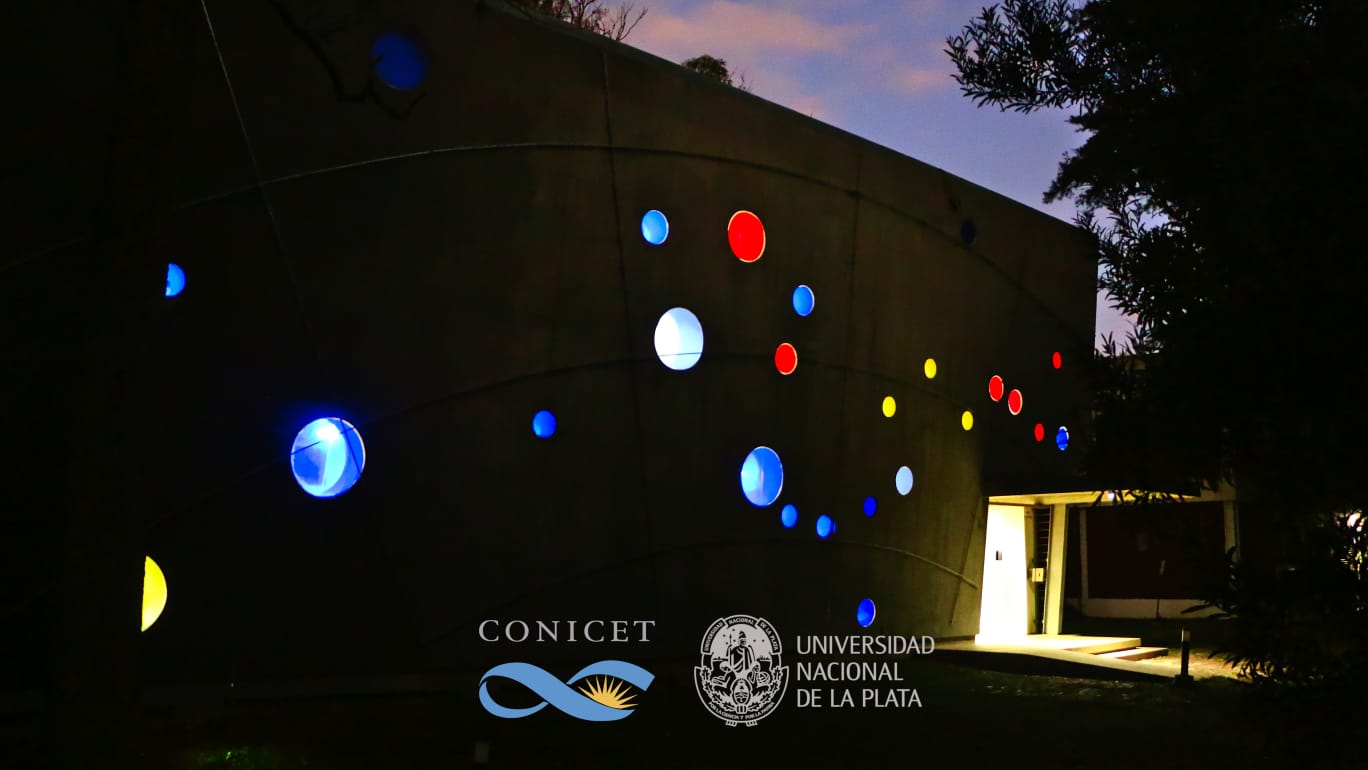 Una vista nocturna del edificio del IALP, cuyas ventanas circulares de colores representan a la Cruz del Sur y las estrellas que la rodean. La luz interior hace que las ventanas brillen como si fueran estrellas.